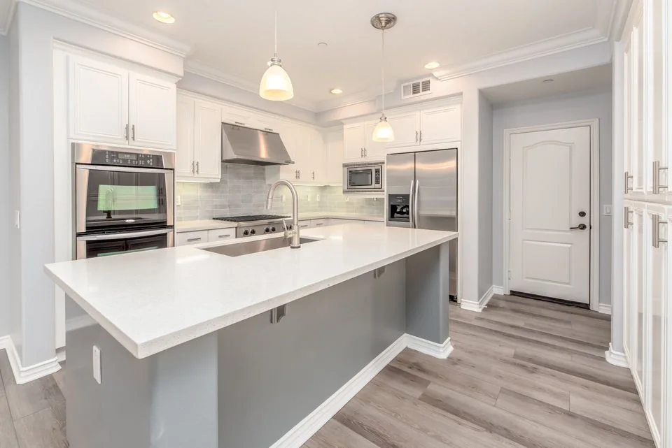 Bright kitchen with white cabinetry, stone benchtops and a wide island