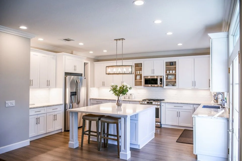 White kitchen with an island bench, cabinetry and pendant lights